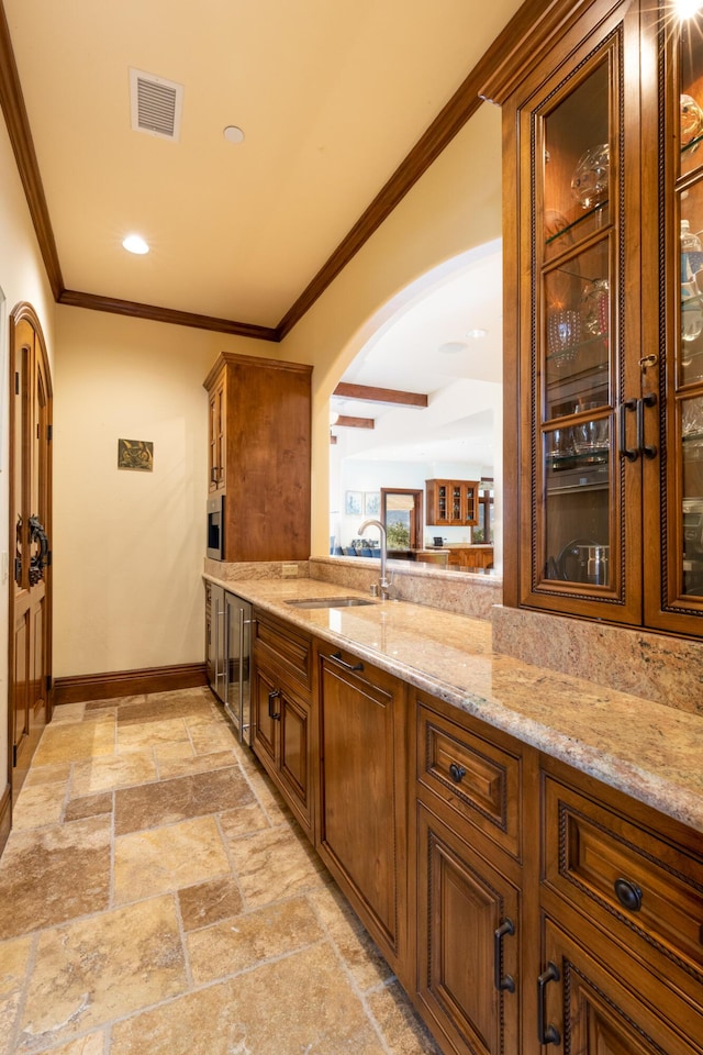 bar featuring ornamental molding, light stone countertops, and sink