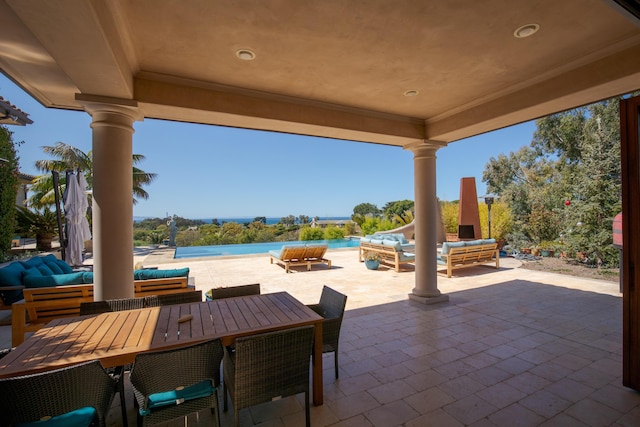 view of patio with a water view and an outdoor living space with a fireplace