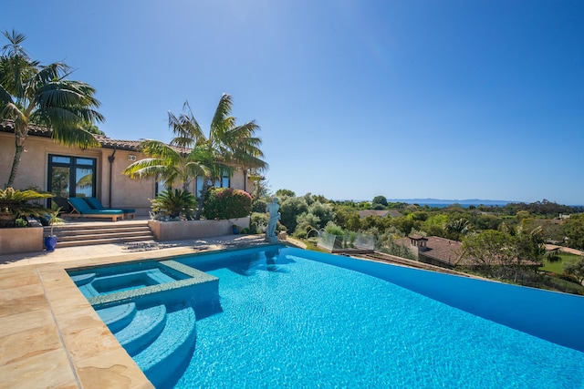 view of pool with french doors and an in ground hot tub