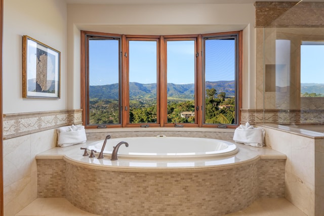 bathroom with tile walls, a mountain view, and tiled bath