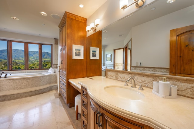 bathroom featuring tile patterned flooring, vanity, tiled bath, a mountain view, and decorative backsplash