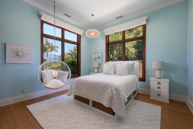 bedroom featuring an inviting chandelier, ornamental molding, and light wood-type flooring