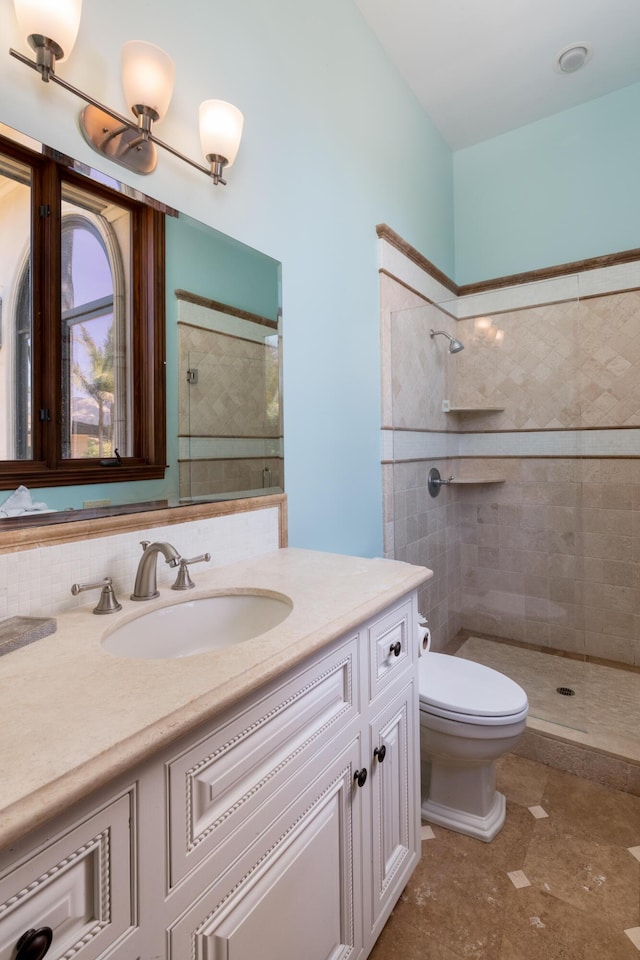 bathroom featuring vanity, tiled shower, and toilet