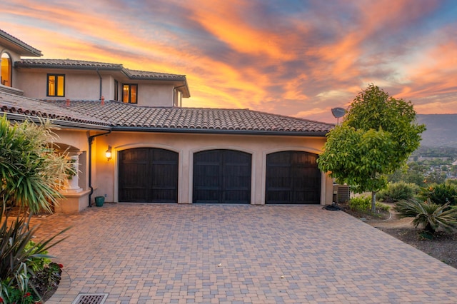 mediterranean / spanish-style house featuring central AC unit and a garage