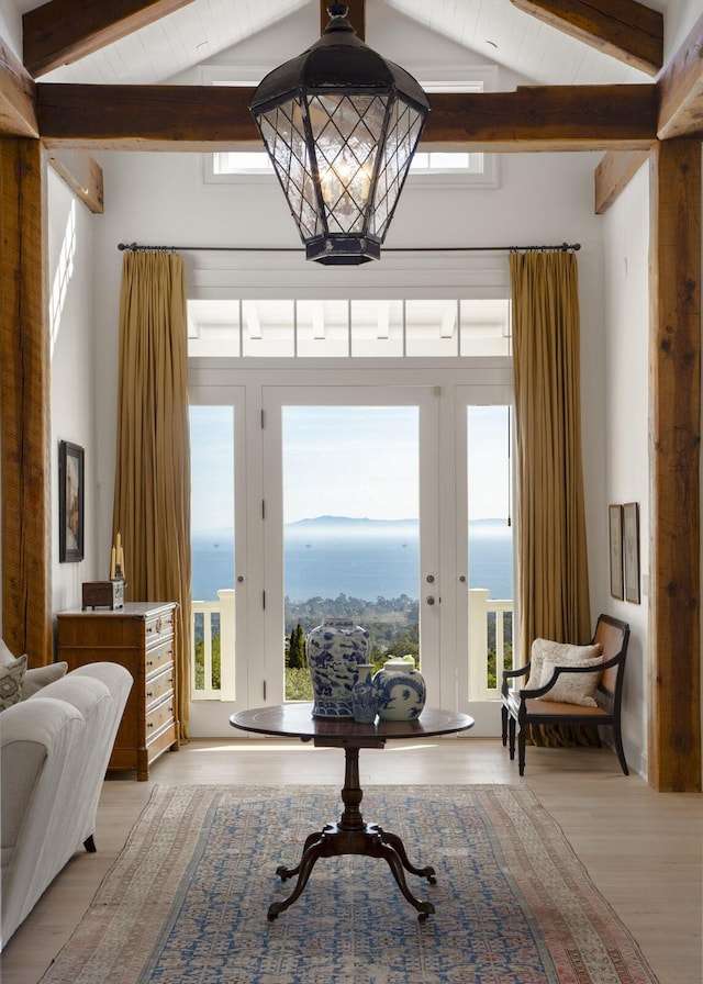 living area with a healthy amount of sunlight, a water view, light wood finished floors, and an inviting chandelier