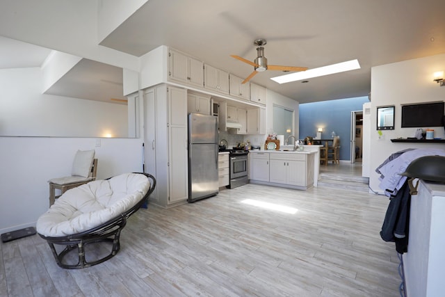 kitchen with a skylight, appliances with stainless steel finishes, light hardwood / wood-style floors, and kitchen peninsula