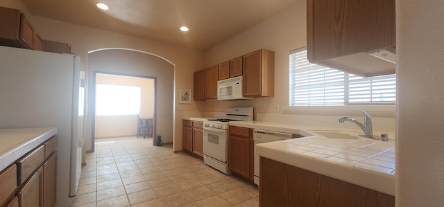 kitchen featuring sink, tile countertops, white appliances, and light tile patterned floors