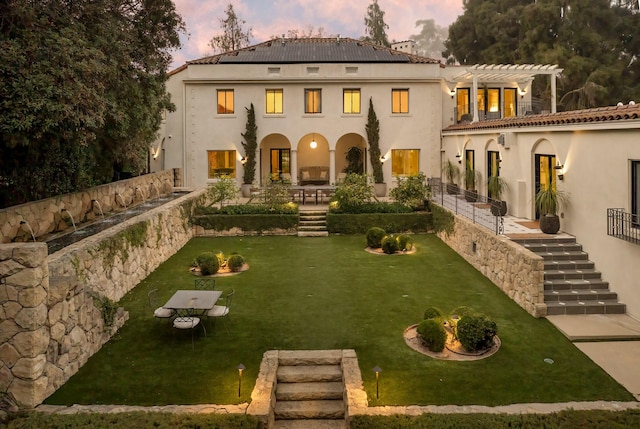 back house at dusk with a patio and a pergola