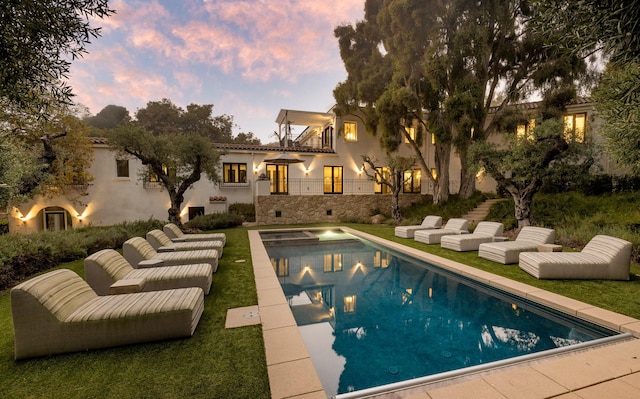 pool at dusk featuring a lawn