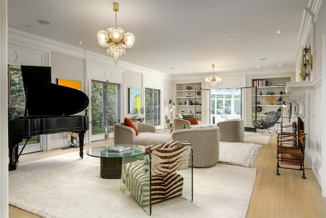 living room featuring crown molding, light hardwood / wood-style floors, built in shelves, and a notable chandelier