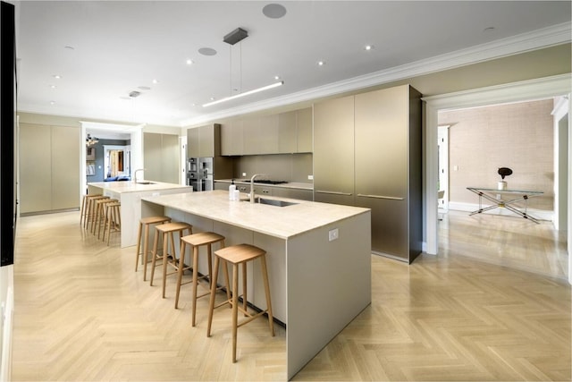 kitchen with sink, crown molding, hanging light fixtures, a spacious island, and light parquet flooring