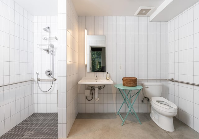 bathroom featuring a tile shower, toilet, and tile walls