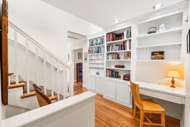 office with built in desk and light hardwood / wood-style floors