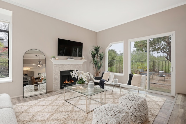 living room featuring crown molding, a healthy amount of sunlight, and light wood-type flooring