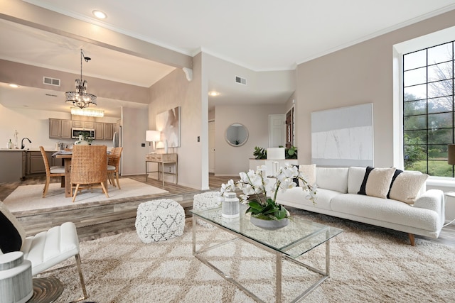 living room with crown molding, a notable chandelier, and light hardwood / wood-style floors