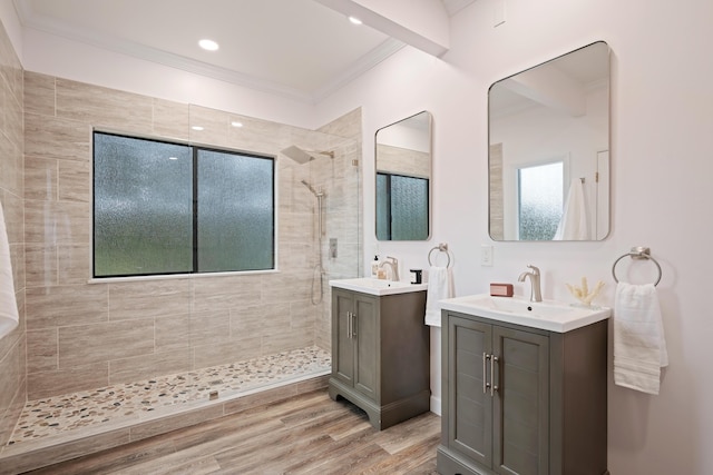 bathroom featuring hardwood / wood-style flooring, crown molding, tiled shower, and vanity