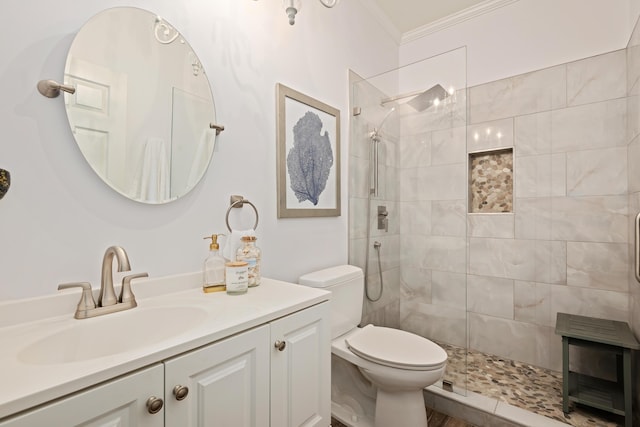 bathroom featuring vanity, crown molding, toilet, and a tile shower