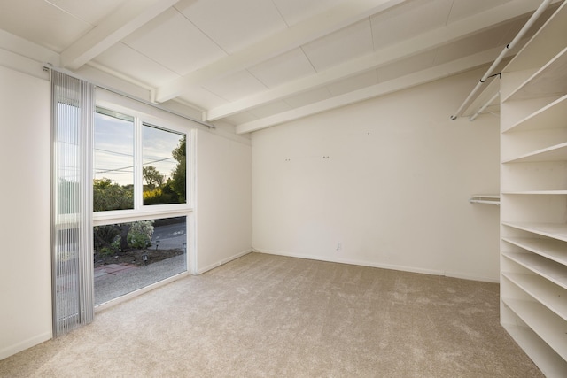 empty room featuring light colored carpet, lofted ceiling with beams, and baseboards