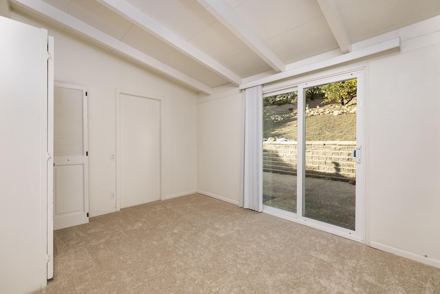 spare room featuring vaulted ceiling with beams and light colored carpet