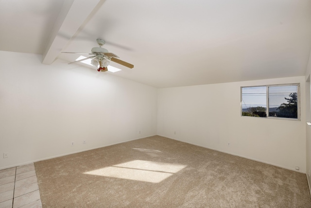 empty room featuring light colored carpet, vaulted ceiling with beams, and ceiling fan