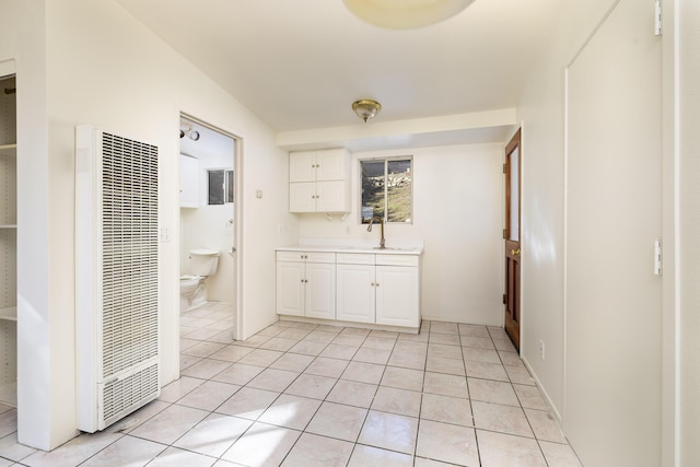 interior space with a heating unit, a sink, and light tile patterned flooring