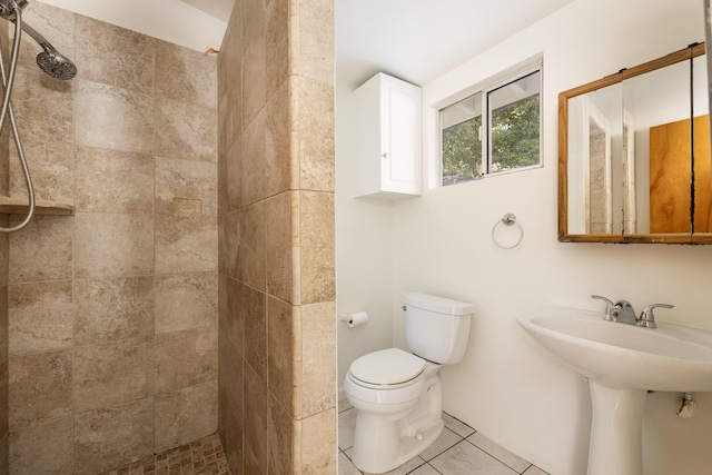 bathroom featuring toilet, tiled shower, and tile patterned floors