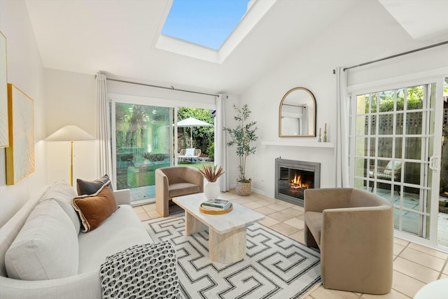 living room featuring lofted ceiling with skylight, a glass covered fireplace, and light tile patterned floors