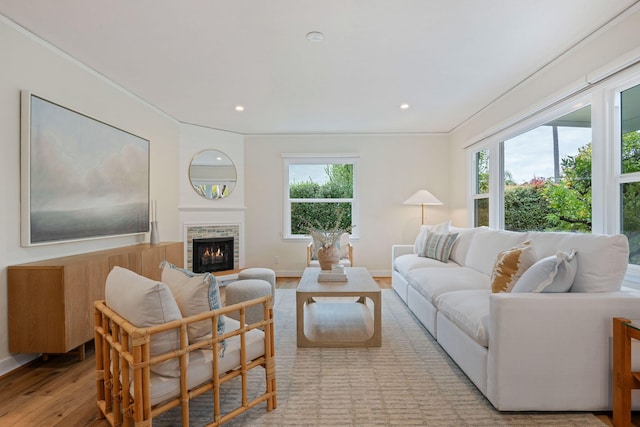 living room with ornamental molding, light hardwood / wood-style floors, a brick fireplace, and a wealth of natural light