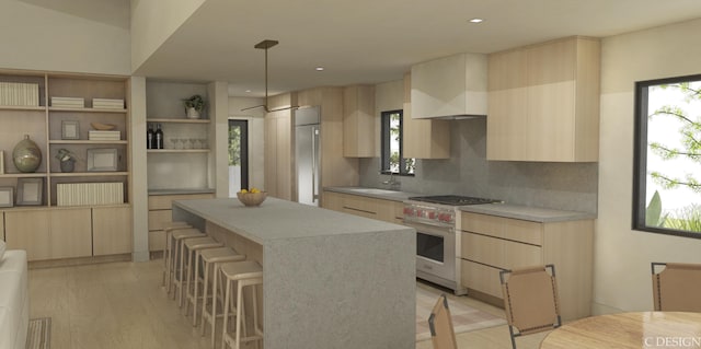 kitchen with wall chimney range hood, hanging light fixtures, a center island, wall oven, and built in fridge