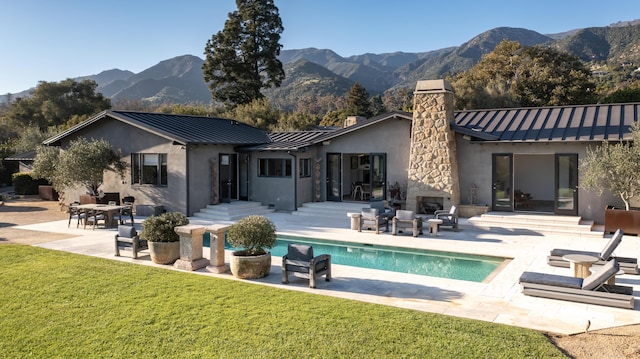 rear view of house with a mountain view, a yard, a fireplace, and a patio area