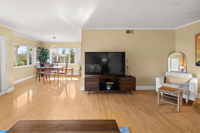 living room with ornamental molding, baseboards, visible vents, and light wood finished floors