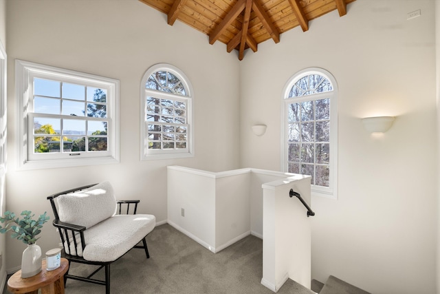 sitting room with light colored carpet, wooden ceiling, and vaulted ceiling with beams