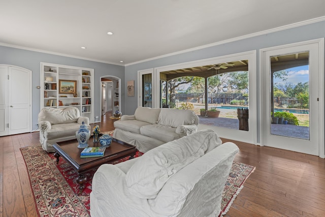 living room featuring wood-type flooring, built in features, and crown molding