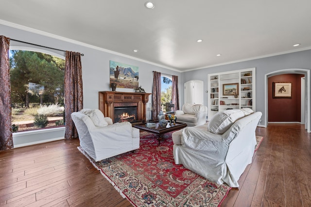 living room with built in shelves, a fireplace, ornamental molding, and dark hardwood / wood-style floors