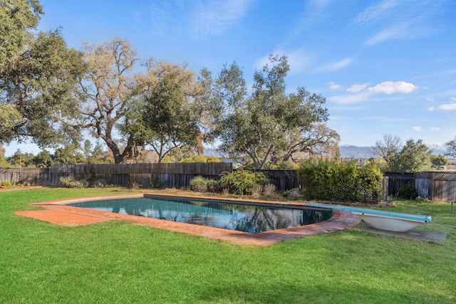 view of swimming pool with a diving board and a lawn