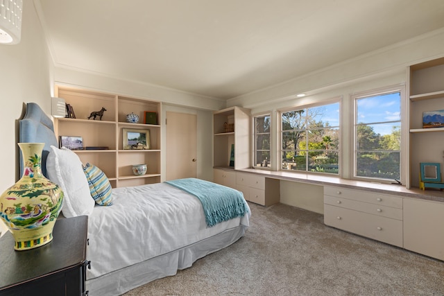 bedroom featuring crown molding, light colored carpet, and built in desk