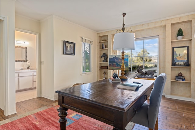 home office featuring crown molding, wood-type flooring, built in features, and a wealth of natural light