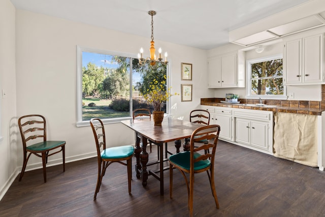 dining space with dark wood-type flooring, sink, and an inviting chandelier