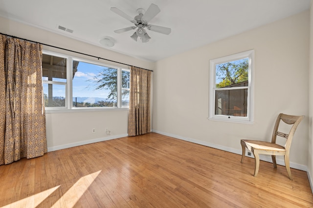 empty room featuring ceiling fan, plenty of natural light, and light wood-type flooring