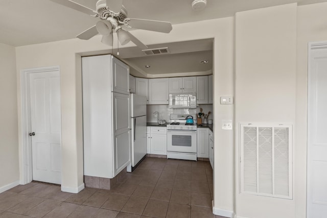 kitchen with dark tile patterned floors, tasteful backsplash, ceiling fan, and white appliances