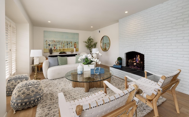 living room featuring hardwood / wood-style flooring, brick wall, and a fireplace