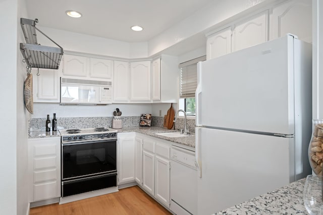 kitchen featuring white cabinetry, sink, light stone countertops, white appliances, and light hardwood / wood-style flooring