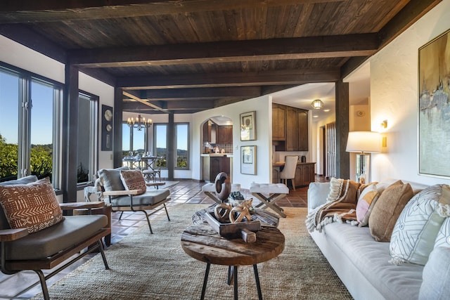 living room with a notable chandelier, wood ceiling, a wealth of natural light, and beamed ceiling