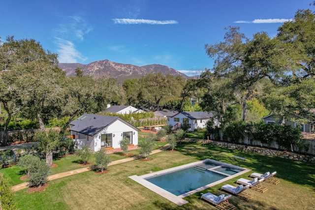 exterior space featuring a fenced in pool, a mountain view, and a lawn