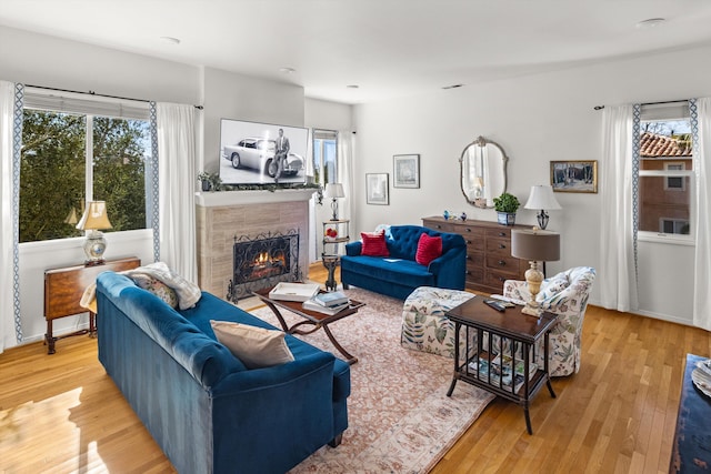 living room featuring a tile fireplace and light wood-type flooring