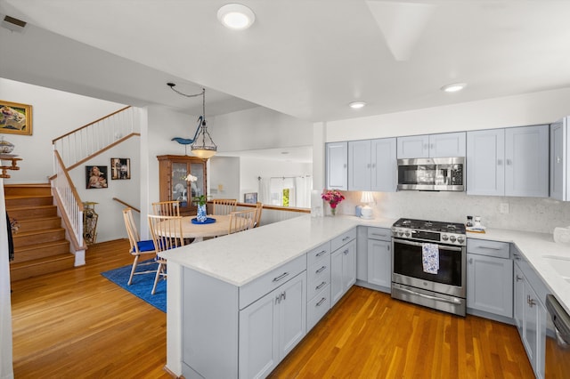 kitchen featuring gray cabinetry, hanging light fixtures, kitchen peninsula, and appliances with stainless steel finishes