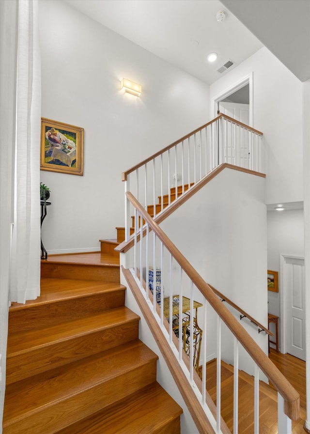 stairs with a high ceiling and wood-type flooring