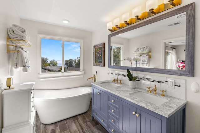 bathroom featuring a healthy amount of sunlight, vanity, decorative backsplash, and a bathing tub