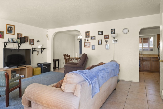 living room with a textured ceiling, sink, and light tile patterned flooring