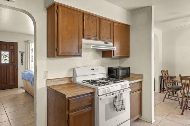 kitchen with light tile patterned floors and white gas range